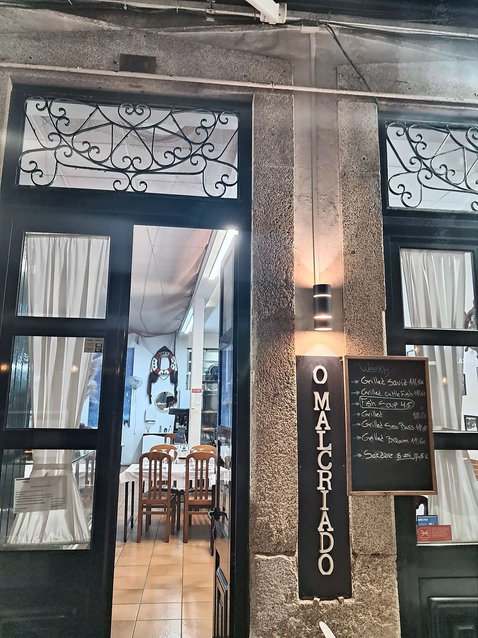 Entrada do restaurante com o letreiro O Malcriado e a ardósia do dia