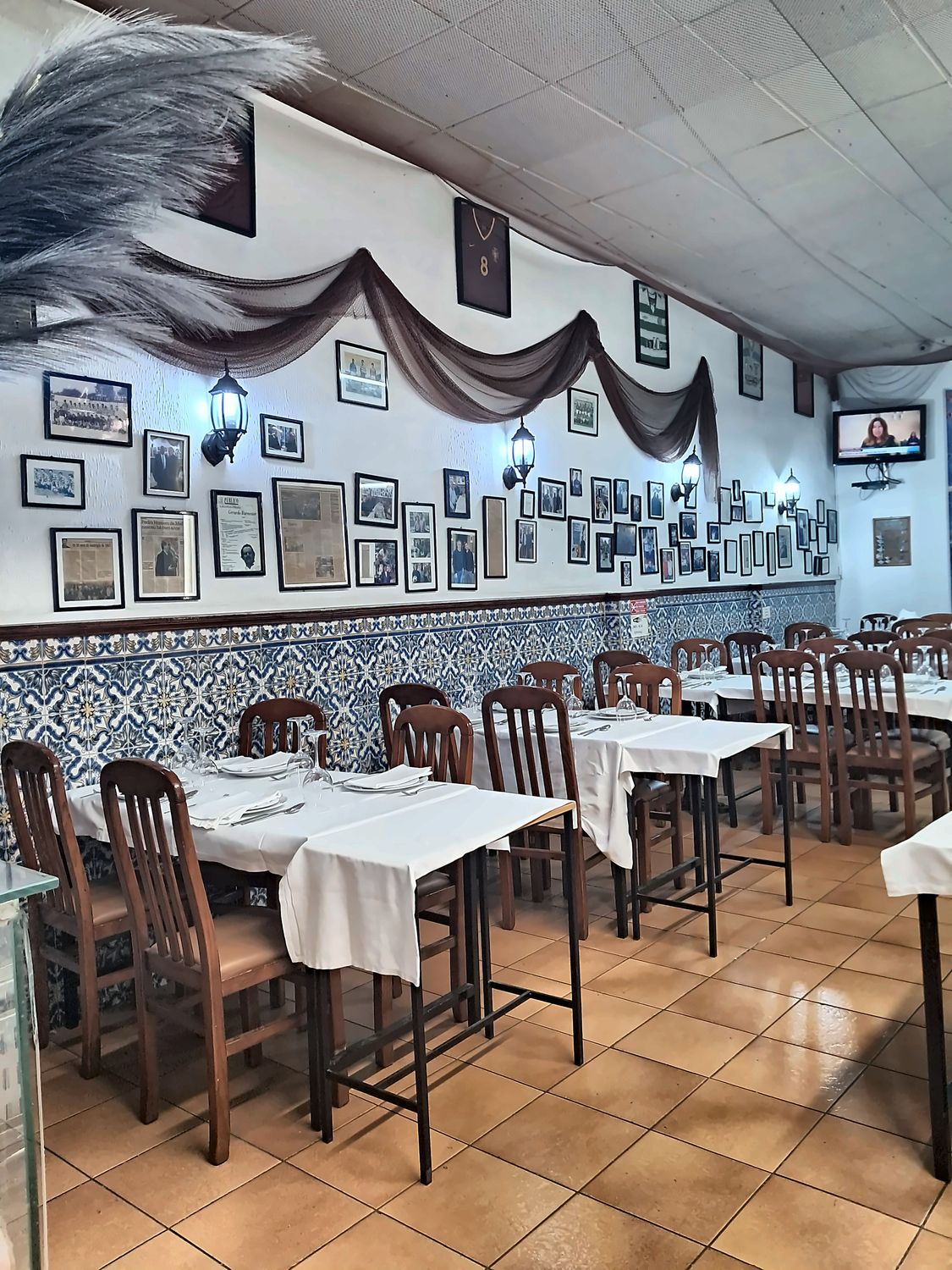 Sala do restaurante O Malcriado com azulejos azuis, mesas postas e fotografias emolduradas na parede